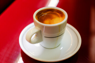 Close up beautiful white coffee cup with foam of morning, breakfast espresso with latte art on the black vintage red table Dark black and white space background Trendy toning Hot Latte Art coffee