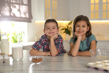 Wall Mural - Cute little children at table with cooking ingredients in kitchen