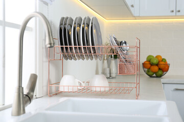 Poster - Clean dishes on drying rack in modern kitchen interior