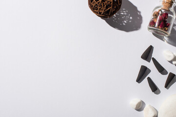 Wall Mural - top view of black incense cones, stones, aroma flowers and decorative ball on white background