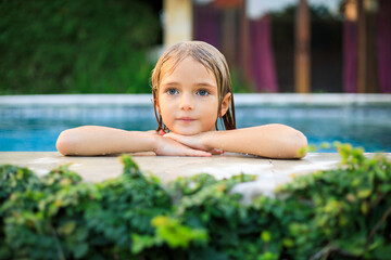 Portrait of charming little girl in the swimming pool. Cute face and wet blond hair. Summer concept. Vacation in Asia. Happy childhood.