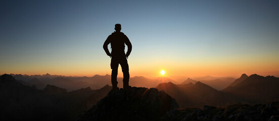 Poster - Man Silhouette reaching summit enjoying freedom and looking towards mountains sunset. Allgau Alps, Bavaria, Germany and Tyrol Austria.