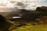 Fototapeta Góry - Scenic view of Quiraing mountains in Isle of Skye, Scottish highlands, United Kingdom. Sunrise time with colourful an rayini clouds in background.