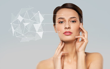 beauty, future technology and people concept - beautiful young woman with low poly shape projection pointing to her face skin over grey background