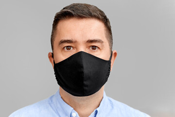 health protection, safety and pandemic concept - portrait of middle-aged man in black reusable face protective mask over grey background