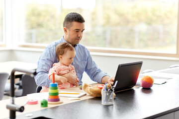 Poster - remote job, multi-tasking and family concept - middle-aged father with baby working on laptop at home office