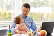 © Syda Productions - remote job, multi-tasking and family concept - middle-aged father with baby working on laptop at home office