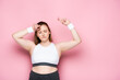 © LIGHTFIELD STUDIOS - excited overweight girl dancing with closed eyes on pink