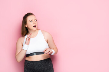 scared overweight girl gesturing while looking away on pink