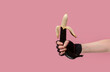 Hands holding a painted black banana on a pastel background. Concept for sex shops, adult toys