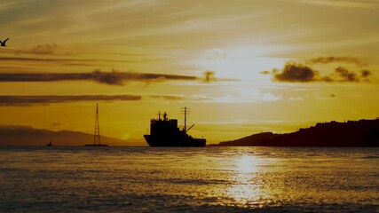 Canvas Print - Time laps of the seascape with a view of the silhouettes of the ship and the city against the sunset. Vladivostok, Russia