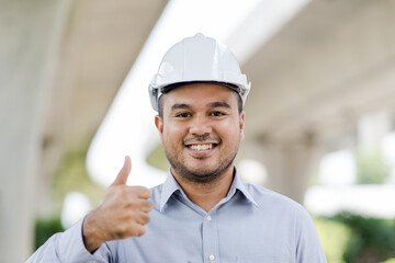 Portrait engineer handsome man or architect looking construction with white safety  helme in construction site.. helmet in construction site.