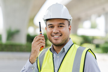 Portrait engineer handsome man or architect looking construction with the command of a radio. and white safety  helmet in construction site.