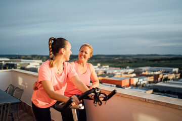 Mother and daughter do bicycle exercises on terrace of house