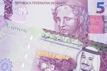 A five Saudi riyal bank note with a pink and purple five Brazilian reais bill.  Shot in macro.