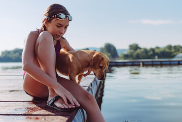 Girl sitting on the river dock with her dog