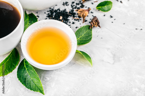 Fotografía Herbal tea, cups and teapot with leaves on grey concrete background