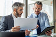 © PhotoAlto - Businessmen discussing over document and digital tablet
