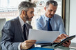 © PhotoAlto - Businessmen discussing over document and digital tablet