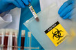 © Tetra Images - Lab professional putting vial into string bag with biohazard sign