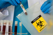 Lab Professional Putting Vial Into String Bag With Biohazard Sign