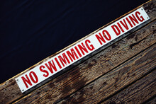 No Swimming No Diving Sign At The Edge Of Wooden Jetty