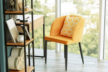 Home Office. By the panoramic window is a wooden table with a laptop, a yellow armchair, and a bookcase. Workplace at home.