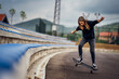 © kerkezz - Teenage girl performing skateboard tricks on the sports field.