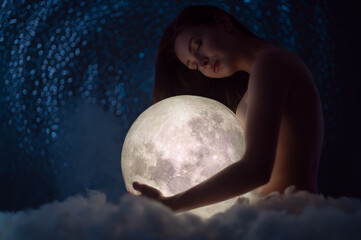 Wall Mural - female tenderness, a beautiful girl holds the moon against the background of stars and sky, zodiac a