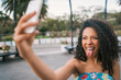 © Mego-studio - Afro American latin woman taking a selfie with phone.