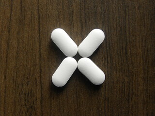 Small oblong shape white medicine tablets on wood background