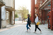 © PR Image Factory - side view full length of two asian japanese women friends relax sightseeing in old factory tourist attraction. group of sisters in fashion wears walking in street while visiting vintage red building.