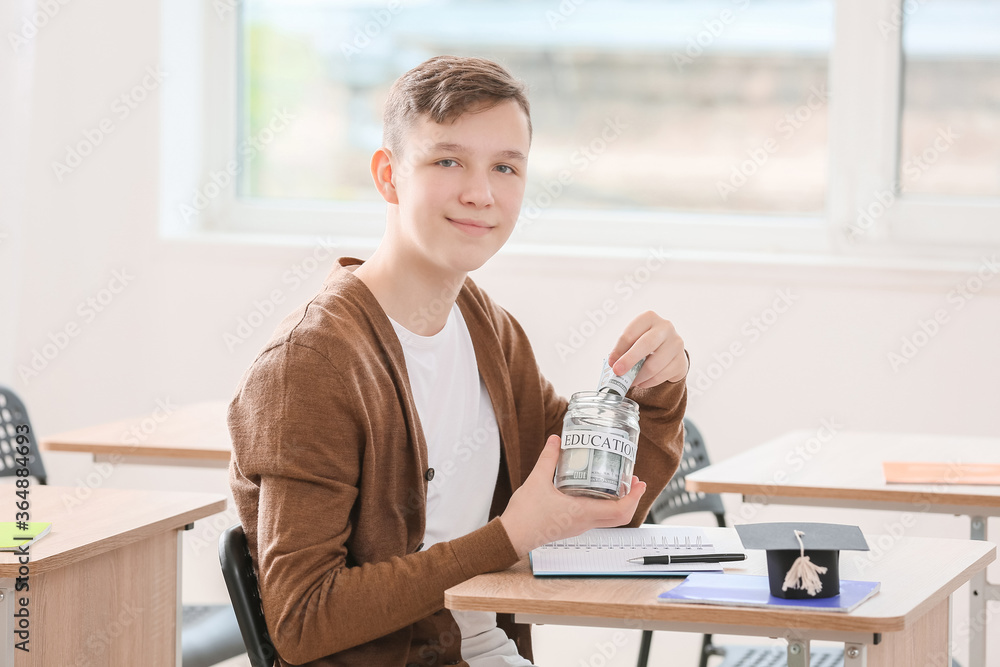 Teenage boy with savings for education in classroom
