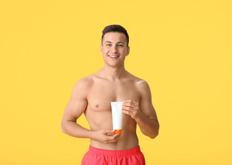 Wall Mural - Happy young man with sun protection cream on color background