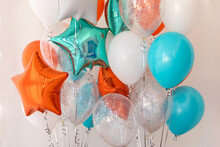 Composition Of Blue, Silver, Orange And Transparent Balloons With Helium. Foil Balloon In The Shape Of A Star. The Concept Of Decorating A Room With Helium Balloons For Holidays Or Birthdays