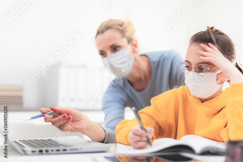 Child home studying education, homeschooling, with private tutor / mother with protective mask in the time of viruses, flu and seasonal pandemic, healthy approach in social contact.