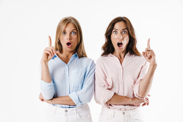 Image of shocked beautiful two women pointing fingers upward