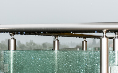 Rain drops on the balcony railing and glass.