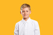 © Photodrive - Happy kid portrait. Back to school. Confident blond boy in white shirt smiling isolated on orange background.