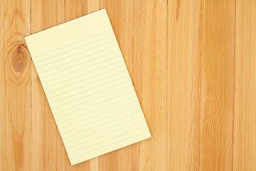 Canvas Print - Yellow legal notepad paper with lines on pine wood desk