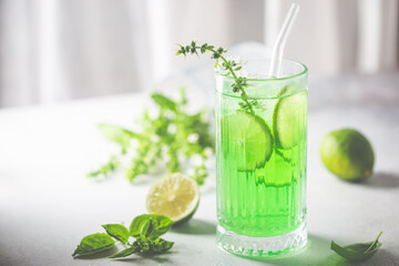 Summer green drink, lemonade with lime, basil and ice in a glass