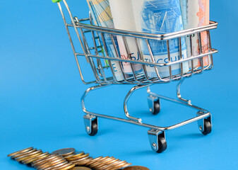 Russian paper rubles in a trolley on a blue background. Metal Russian coins. World economic crisis. Cash loan. Selective focus.