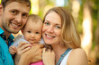 © Sk Elena - Happy family spent time together outdoors. Portrait of mother, father and baby looking at camera. Summer time.