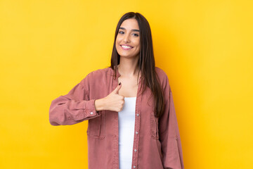 Wall Mural - Young brunette woman over isolated yellow background giving a thumbs up gesture