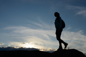 Wall Mural - young woman traveler hiking with backpack on the beautiful rocky trail at summer sunset. travel and 