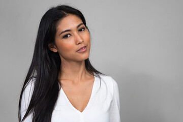 Portrait of young beautiful Asian woman against white background