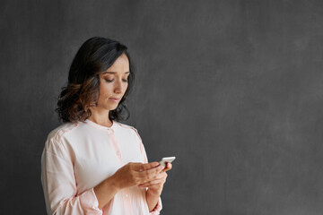 Wall Mural - Young Asian businesswoman using a cellphone by a blank chalkboard