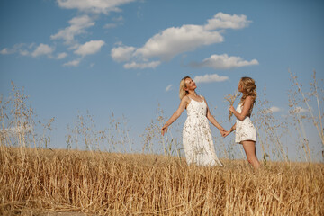 Wall Mural - Adult mother with daughter. Beautiful girl in a white dress. Family in a summer field