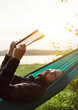 © mykolastock - Bearded hipster male reading book in hammock