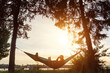 © mykolastock - Silhouette of freelancer working in hammock in park at sunset